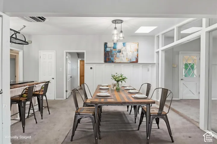 Board and batten wainscoting, glass-paned interior door, ceiling-mounted multi-light fixture, and recessed skylight