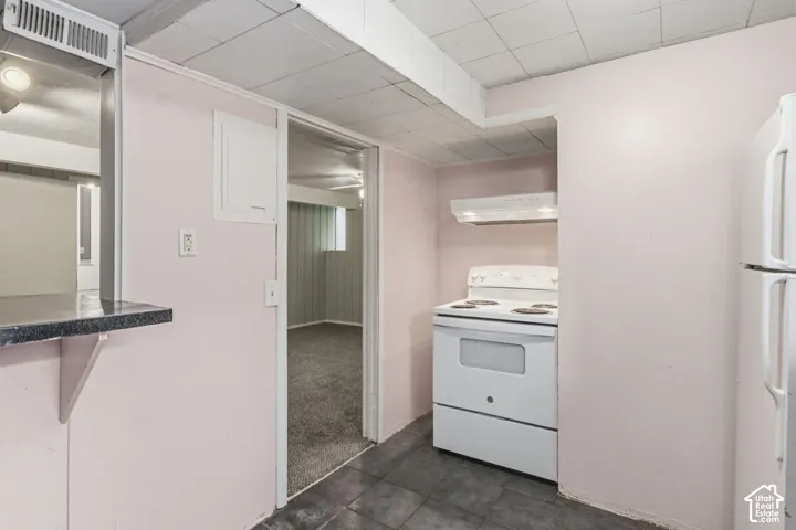 Kitchen featuring a white electric range, integrated hood, tile flooring, and a passthrough counter