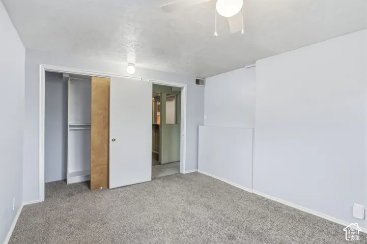 Room featuring neutral wall tones, carpeted flooring, a ceiling fan with integrated lighting, and a closet with a swing door