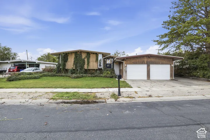 Mid-century modern exterior featuring wood-paneled siding, a low-slung roofline, vertical accent windows, and an attached two-car garage