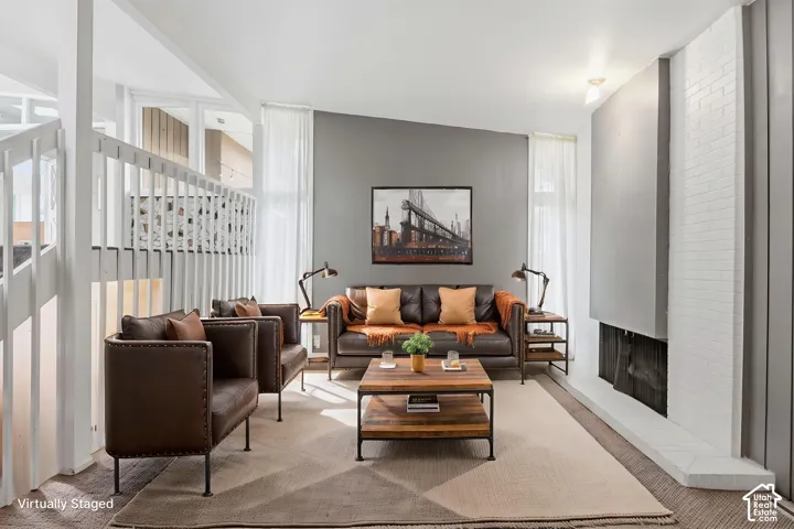 Living area featuring a floor-to-ceiling painted brick fireplace, a high-sloped ceiling, painted wood stair railings, and tall windows