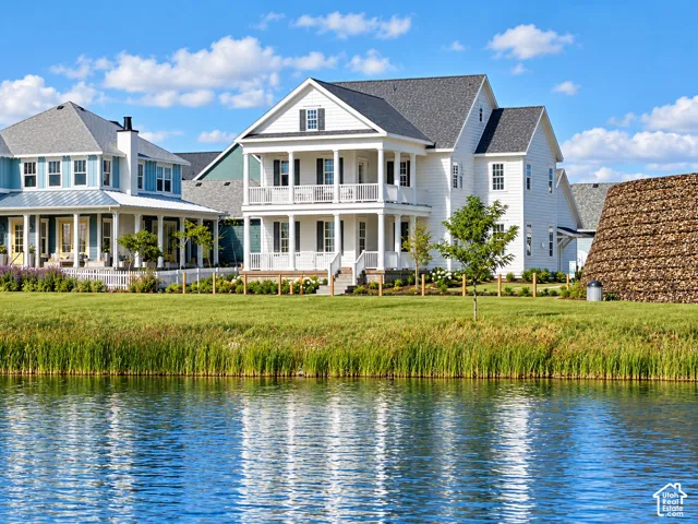 Two-story exterior with white lap siding, dual-level covered porches, dark shingle roofing, and waterfront frontage