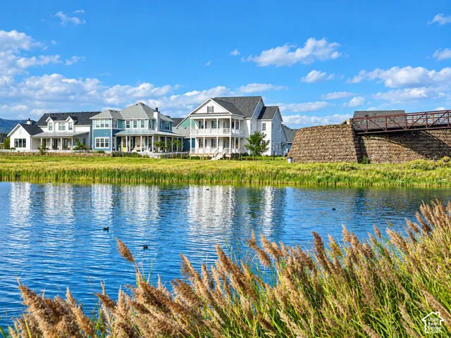 Waterfront property featuring multi-story architectural facades, covered front porches, and a stone-clad pedestrian bridge