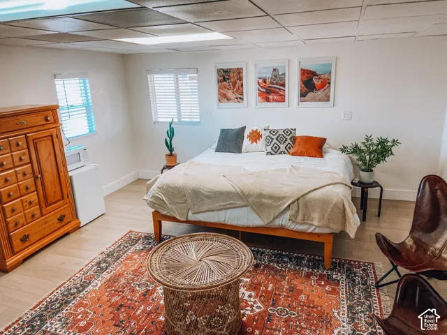 Wood-finish flooring, drop-ceiling panels, and white-framed windows with horizontal blinds