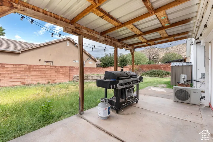 Covered patio featuring a timber-frame structure, metal roofing, concrete flooring, and an enclosed brick perimeter wall