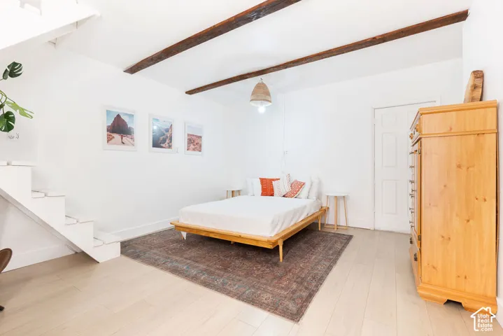 Exposed wood ceiling beams, white-painted wooden staircase, wood-finish flooring, and a pendant light fixture