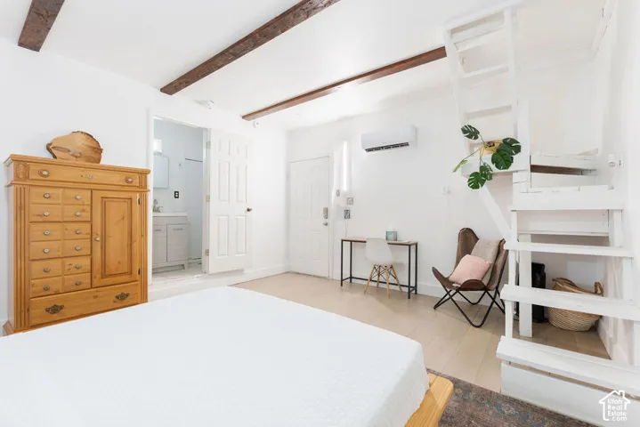 Exposed ceiling beams, white-painted wooden staircase, light-toned wood-finish flooring, and wall-mounted climate control unit