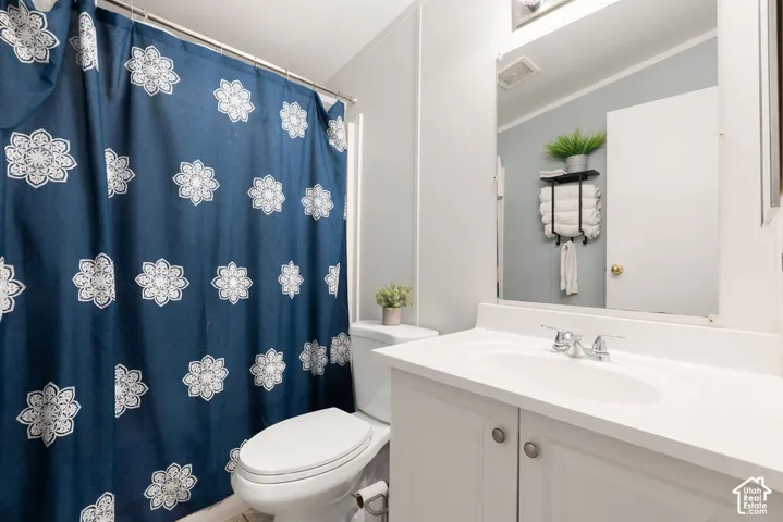 Bathroom featuring a vanity with integrated sink, chrome dual-handle faucet, large wall-mounted mirror, and wall-mounted metal shelving