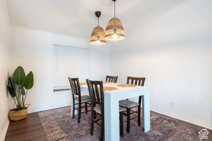 Textured ceiling with dual pendant light fixtures and wood-finish flooring