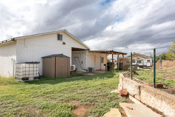 Detached outbuilding with white vertical siding, exterior covered patio area, and raised stone garden beds
