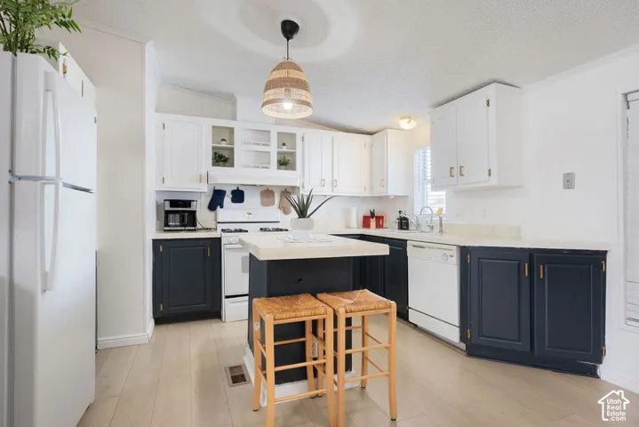 Kitchen featuring dual-toned cabinetry, central island with surface counter space, wood-finish flooring, and pendant lighting