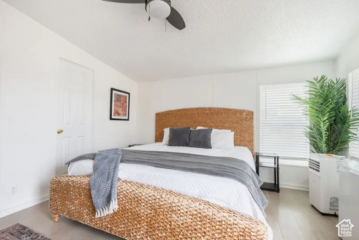 Bright room featuring wood-finish flooring, white walls, horizontal window blinds, and a ceiling fan with integrated lighting