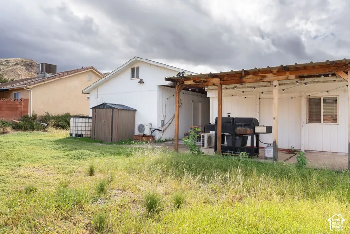 Rear exterior featuring a covered wood-framed patio, concrete slab flooring, and white board-and-batten siding