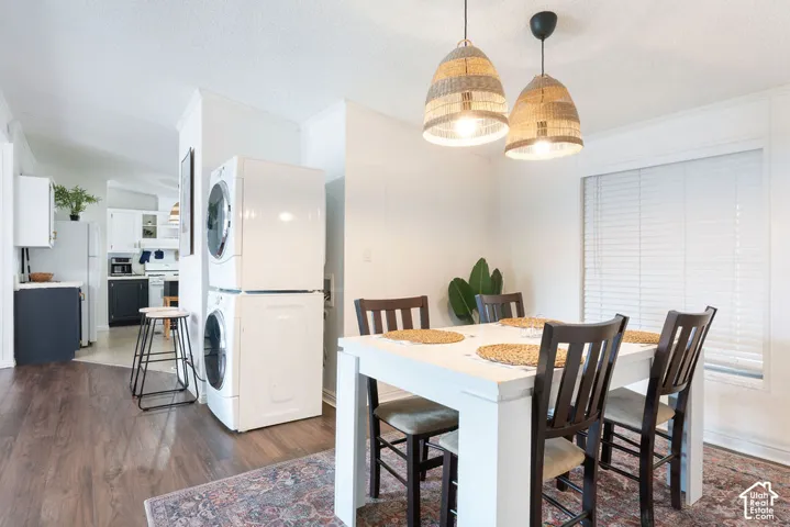 Multi-purpose area featuring wood-finish flooring, dual woven-textile pendant lighting, and a stacked front-loading laundry unit