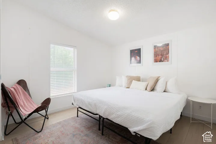 Neutral-toned walls, wood-finish flooring, and window with horizontal blinds