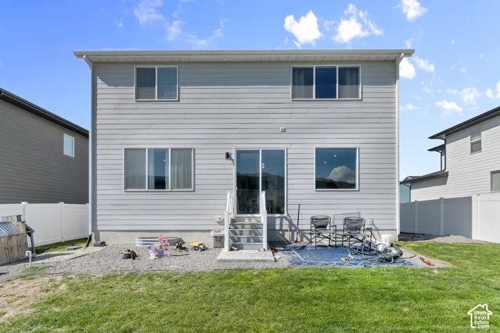 Two-story residence with horizontal siding, sliding glass door, elevated stairs, and vinyl perimeter fencing