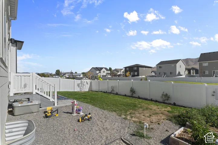 Backyard featuring a white vinyl privacy fence, graveled ground cover, manicured lawn, and raised garden bed