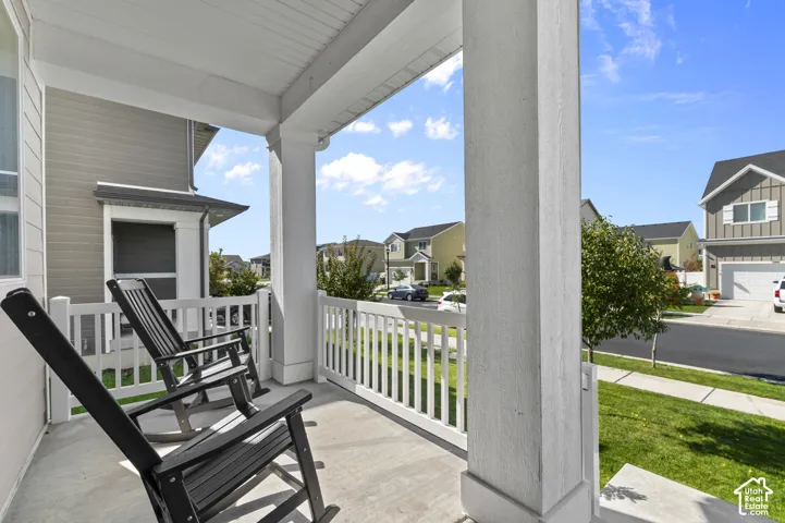 Covered front porch featuring a concrete floor, high-profile square columns, and white vinyl railing