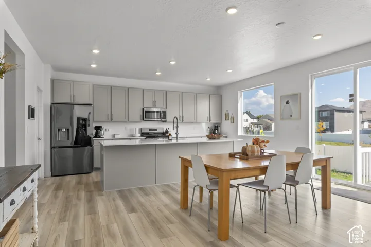 Kitchen featuring flat-panel cabinetry, a central island with a solid-surface countertop, stainless steel appliances, recessed lighting, and wood-finish flooring