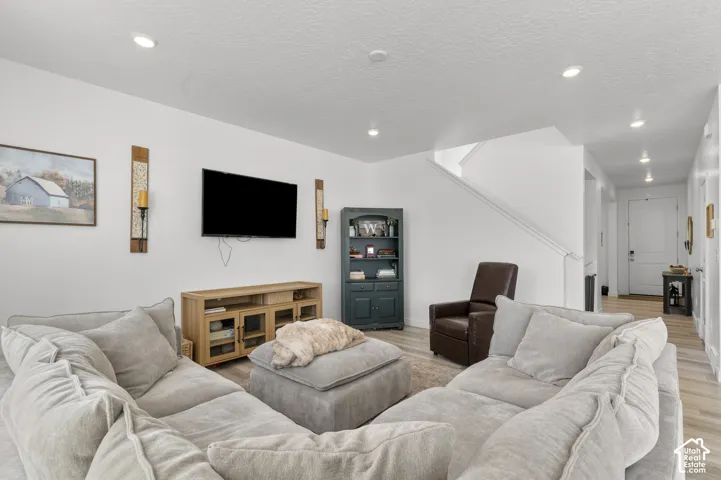 Living area featuring recessed lighting, wood-finish flooring, and a neutral color palette
