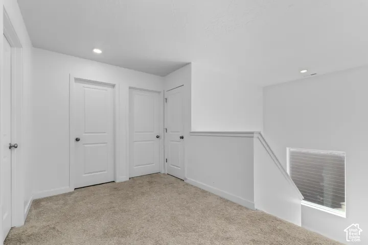 Neutral wall-to-wall carpeting, recessed ceiling lighting, and solid-core interior doors with matte black hardware