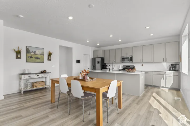 Kitchen featuring shaker-style cabinetry, an expansive center island with a stone-finish countertop, stainless steel appliances, recessed lighting, and wood-finish flooring