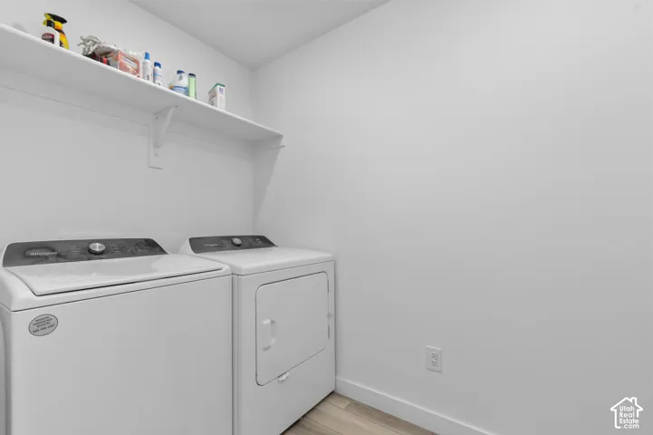 Laundry area featuring wood-finish flooring and a wall-mounted overhead shelf