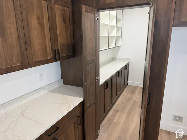 Custom dark wood cabinetry, stone-surface countertops, built-in open shelving, and wood-finish flooring