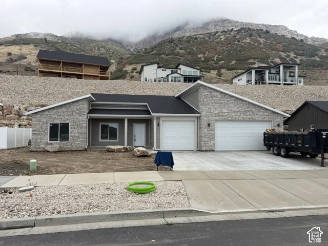 Exterior facade featuring stone veneer masonry, horizontal lap siding, a pitched shingle roof, and an attached three-car garage