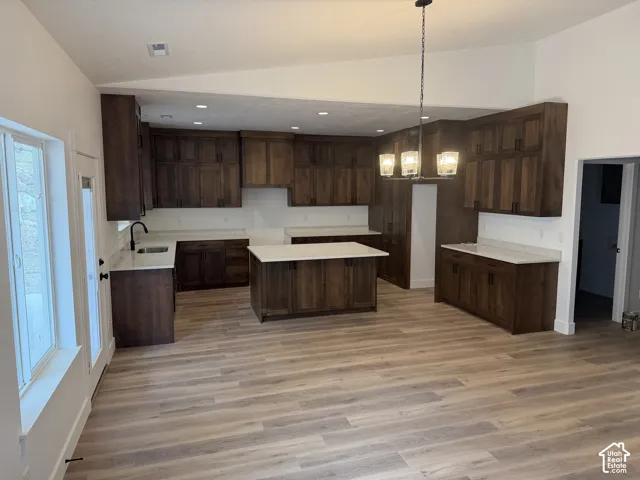 Kitchen featuring wood cabinetry, a central island with a stone-surface countertop, recessed lighting, a chandelier, and wood-finish flooring