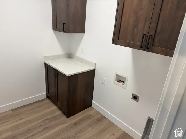 Utility space featuring dark-finish cabinetry, stone-patterned countertop, wood-finish flooring, and matte black hardware