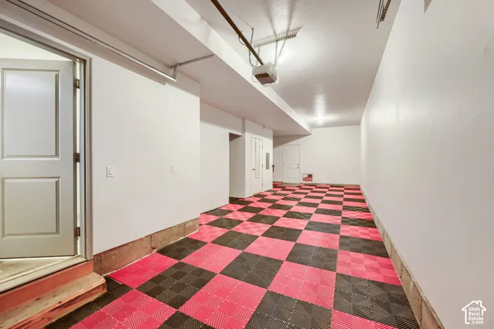 Finished garage featuring interlocking tile flooring, smooth white walls, and multiple door access points