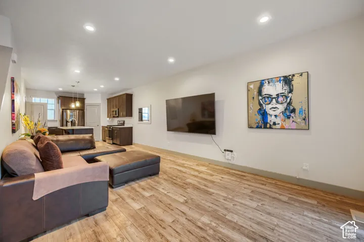 Open-concept interior featuring wood-finish flooring, recessed lighting, and dark-toned cabinetry with light-colored countertops