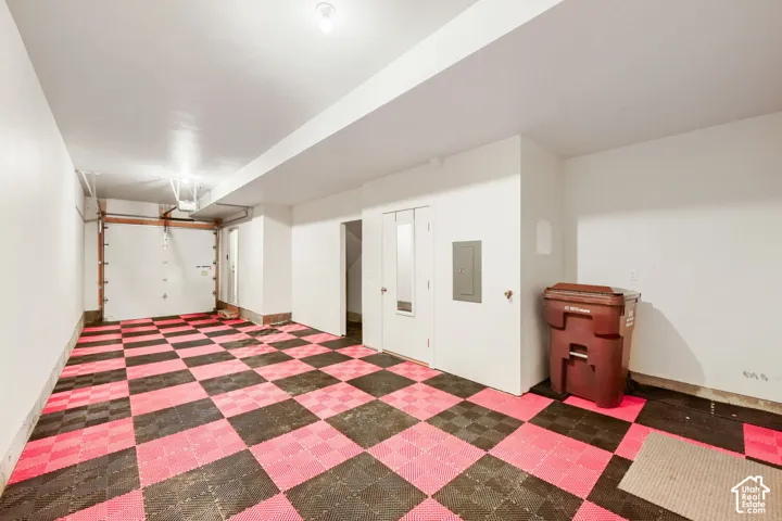 Enclosed garage space featuring high-contrast interlocking floor tiles, bright white wall finishes, and an overhead sectional door