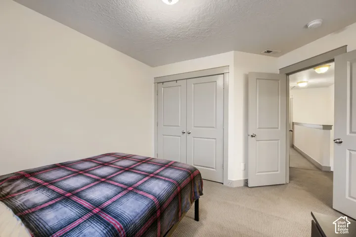 Room featuring neutral wall tones, carpeted flooring, two-panel interior doors, and a double-door closet with matching trim