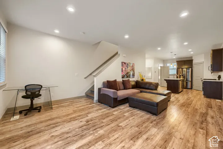 Open-concept area featuring wood-finish flooring, recessed lighting, and a kitchen island with stone countertop