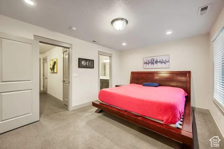 Neutral-toned carpeted flooring, two-panel interior doors with stained wood trim, recessed ceiling lighting, and horizontal window blinds