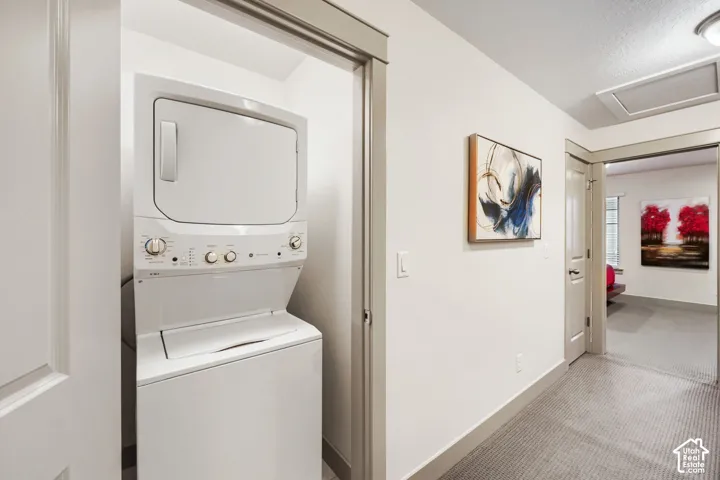 Laundry closet featuring a built-in stackable washer and dryer unit with white finish, neutral-toned interior casing, and doorways with matching trim