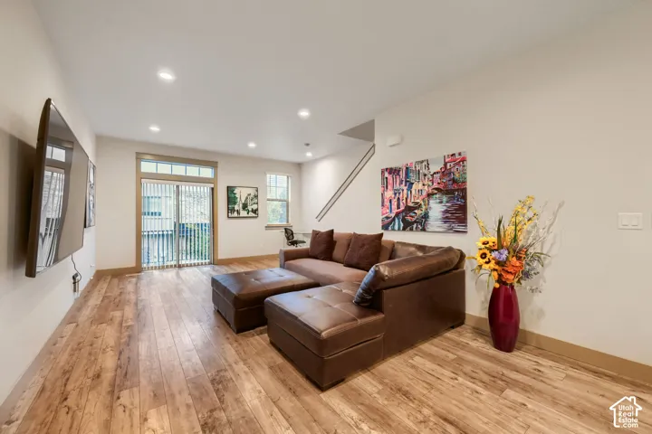 Living area featuring wood-finish flooring, recessed lighting, and a glass sliding door with a transom window