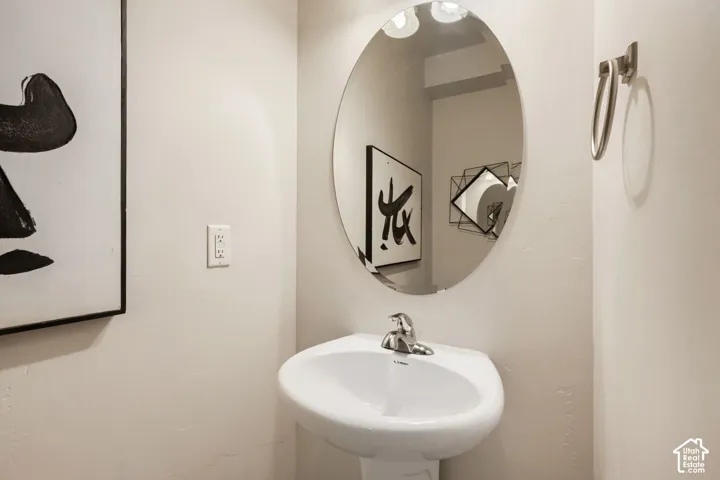 Oval wall-mounted mirror, white pedestal sink, chrome single-handle faucet, and metallic towel ring