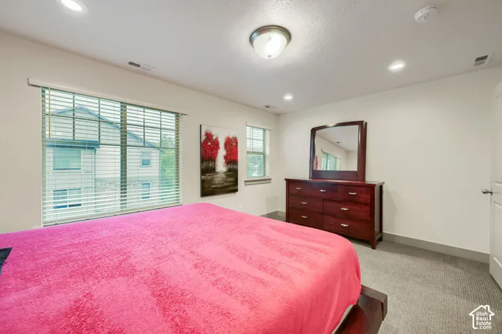 Neutral-toned room featuring neutral carpeting, recessed ceiling lighting, a flush-mount light fixture, and large windows with horizontal blinds