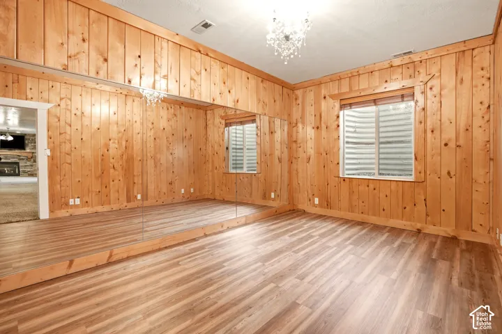 Interior room featuring natural wood-paneled walls, wood-finish flooring, full-height wall mirrors, and an ornamental ceiling chandelier