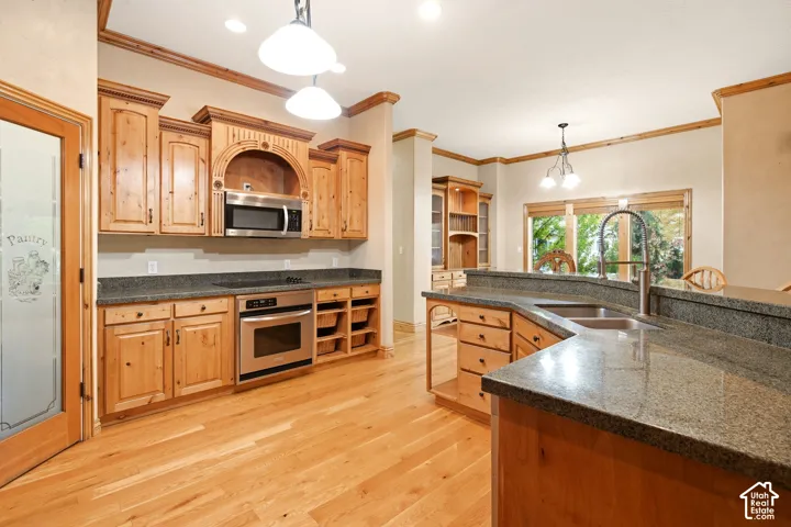 Kitchen featuring natural wood cabinetry, stone countertops, stainless steel appliances, wood-finish flooring, and pantry with an etched glass door