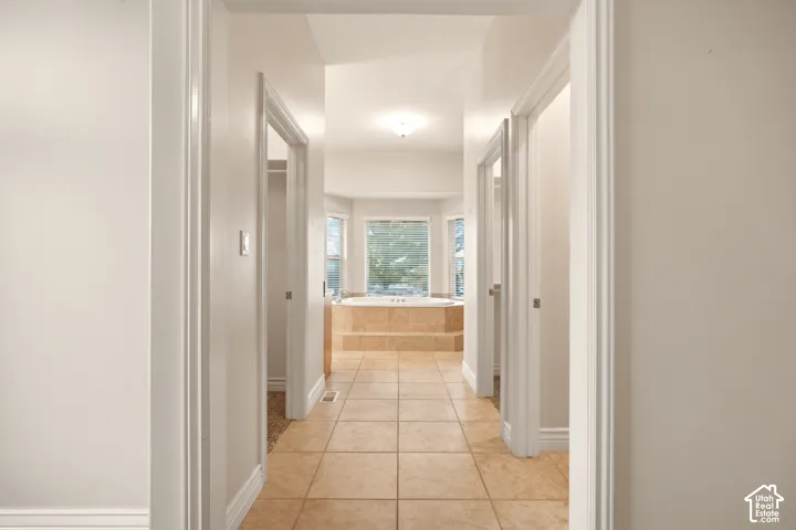Neutral-toned tile flooring, recessed soaking tub with tiled surround, and bay window configuration