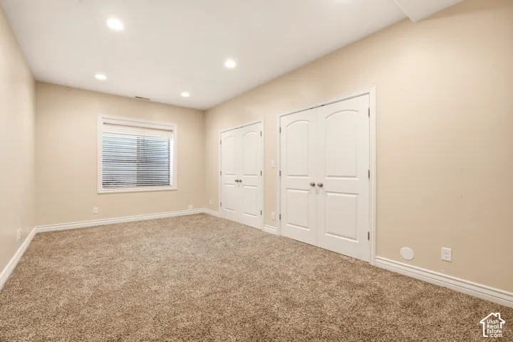 Neutral-toned interior featuring recessed lighting, plush wall-to-wall carpeting, and dual sets of white arched-panel closet doors