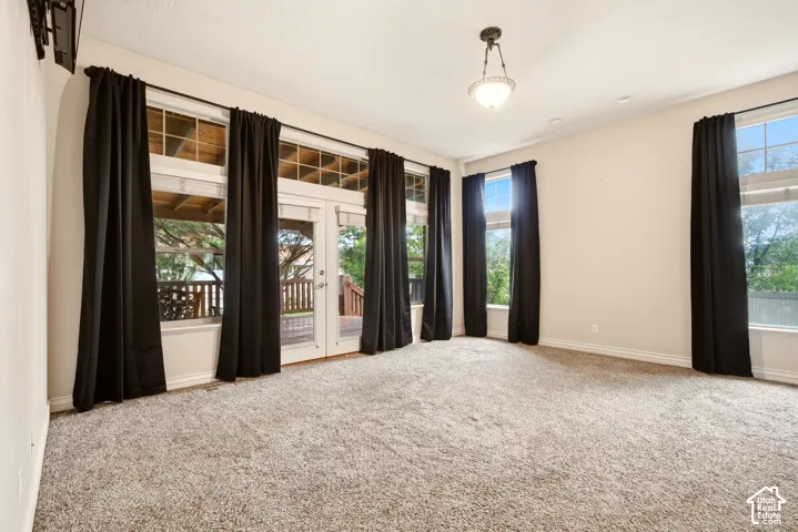 High ceilings featuring a central pendant light, expansive windows with transom glass, and exterior glass-paneled door access