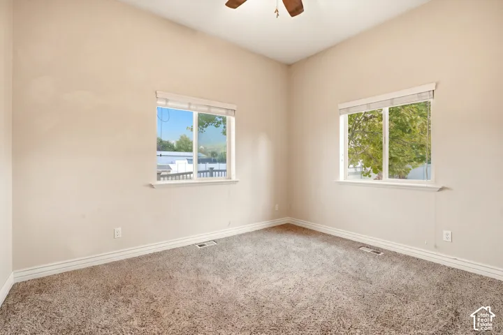Vaulted ceilings, neutral wall tones, dual windows, and an overhead ceiling fan