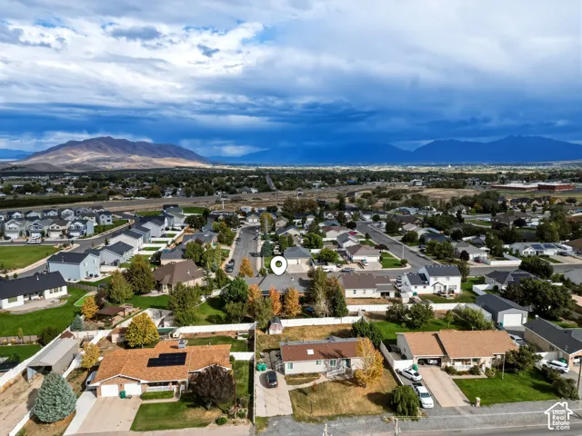 Aerial perspective of a residential property featuring a detached garage, concrete driveway, and mountain backdrop