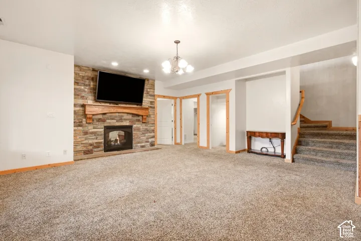 Floor-to-ceiling stone fireplace with wood mantel, built-in recessed shelving, integrated recessed lighting, and chandelier fixture