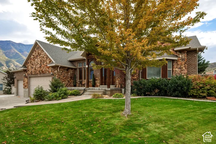 Exterior featuring a stone and brick facade, an attached garage, and mountain scenery